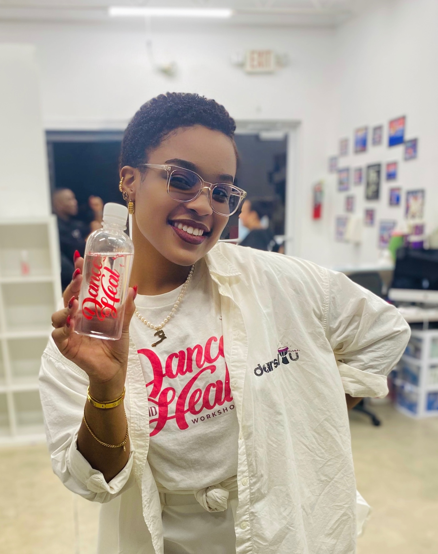 Sephora smiling and holding a branded Dance & Heal water bottle before a workshop.